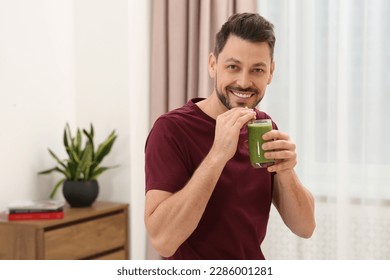 Happy man drinking delicious fresh smoothie at home - Powered by Shutterstock