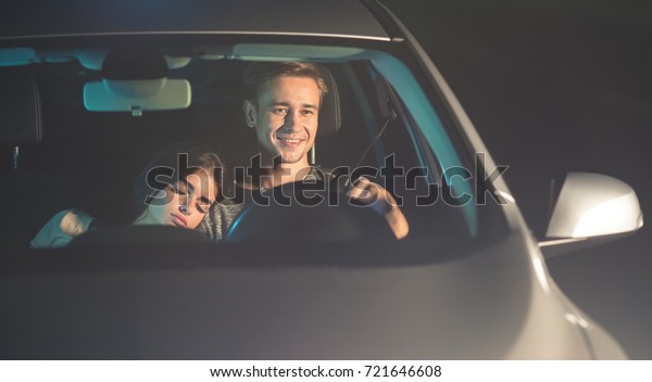 The happy man drive a car with a sleeping woman.\
evening night time