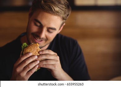 Happy Man Eating Burger In Restaurant