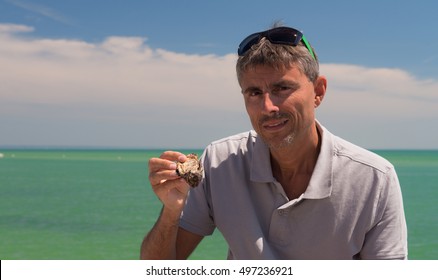 Happy Man Eating Oysters On The Beach.