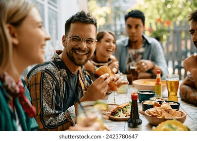 Happy man eating tacos and talking to his friends during their gathering in a restaurant.  - Powered by Shutterstock