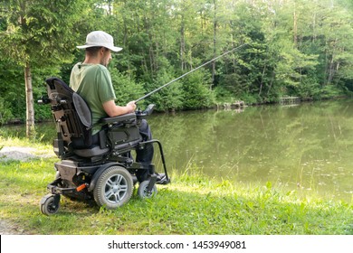 Happy man in a electric wheelchair fishing at the beautiful pond in natue on a sunny day