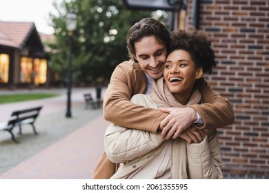 happy man embracing amazed african american girlfriend near building outdoors - Shutterstock ID 2061355595