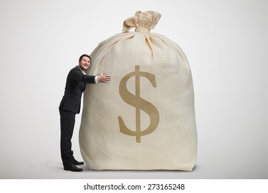 Happy Man Embracing Big Bag With Money Over Light Grey Background