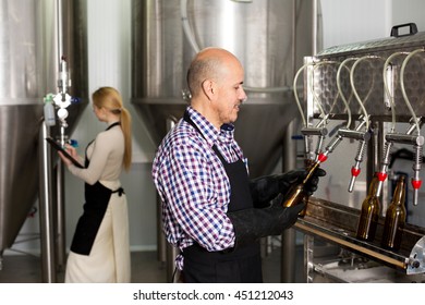 Happy Man Employee Bottling Beer In Glass Bottles On Modern Facility