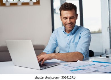 Happy man entering data from home on laptop - Shutterstock ID 308412914