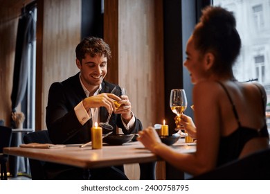 happy man in evening attire holding glass of wine and having dinner with woman in restaurant - Powered by Shutterstock