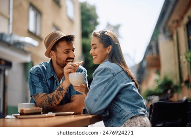 Happy man feeding his girlfriend with a cookie while drinking coffee in sidewalk cafe.  - Powered by Shutterstock