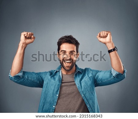 Happy man, fist and celebration for winning, achievement or success against a grey studio background. Excited portrait of male person or winner in victory, win or accomplishment on mockup space