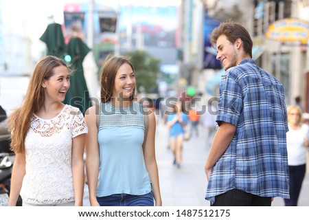 Happy man flirting with tho happy women walking in the street