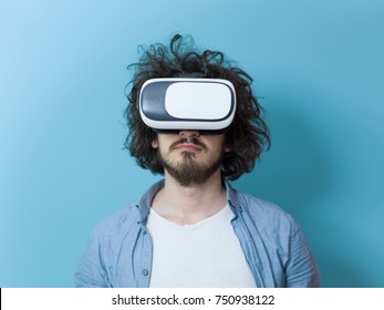 Happy man getting experience using VR headset glasses of virtual reality, isolated on blue background