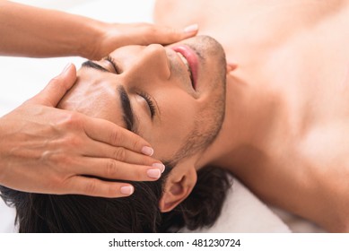 Happy Man Getting Facial Treatment At Massaging Center