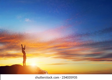Happy man with hands up standing on the peak of the mountain at lovely sunset. Enjoy life!
