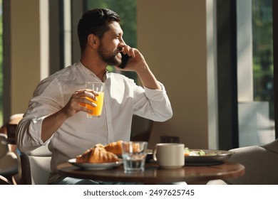 Happy man having tasty breakfast while talking on smartphone in cafe, space for text - Powered by Shutterstock