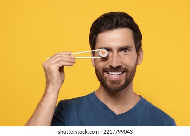 Happy Man Hiding His Eye With Tasty Sushi Roll On Orange Background