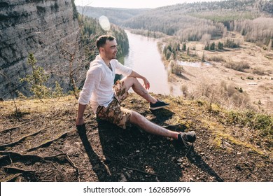 Happy Man hiker sitting at mountain top and looking at scenic landscape - Powered by Shutterstock
