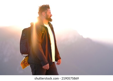 A happy man hiker smiling while walking during the hike on the mountain at sunrise active healthy lifestyle. - Shutterstock ID 2190575869