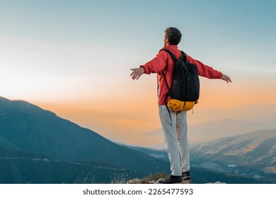 A happy man hiker standing with hands open on the mountain top adventure travel. - Shutterstock ID 2265477593