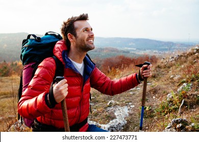 Happy Man Hiking With Backpack During Fall Wearing Down Jacket
