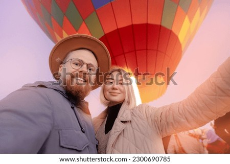 Happy man hipster making selfie photo on phone background hot air balloons in Cappadocia. Concept trip Turkey travel.