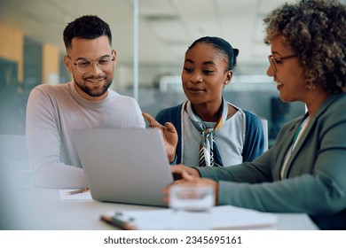 Happy man and his African American wife using computer with their insurance agent during consultations in the office. - Powered by Shutterstock