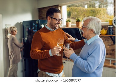 Happy man and his mature father toasting with wine talking in the kitchen.  - Powered by Shutterstock