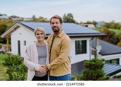 Happy man with his pregnant wife standing in front of their new house with photovoltaics solar panels. - Powered by Shutterstock