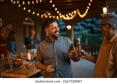 Happy man and his senior father toasting with beer during family gathering on a patio. - Powered by Shutterstock