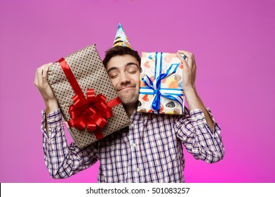 Happy Man Holding Birthday Gifts In Boxes Over Purple Background.