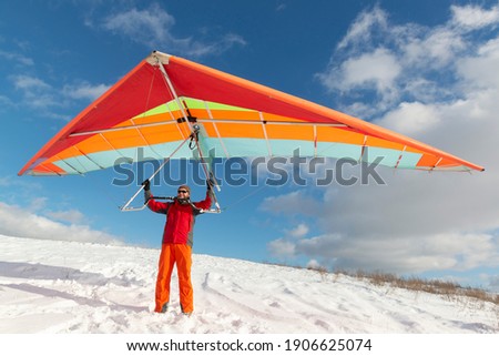 Happy man holding colorful hang glider wing on a slope. Learning to fly