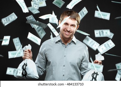 Happy Man Holding Money Bags Looking At Camera With Money Falling Behind