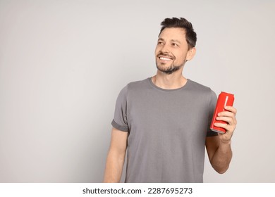 Happy man holding red tin can with beverage on light grey background. Space for text - Powered by Shutterstock