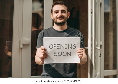 Happy Man Holding Sign With Inscription Opening Soon In Cafe, Restaurant, Shop. Quarantine, Coronavirus, Isolation.