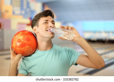 Happy Man Holds Orange Ball And Drinks Water From Bottle In Bowling Club; Shallow Depth Of Field