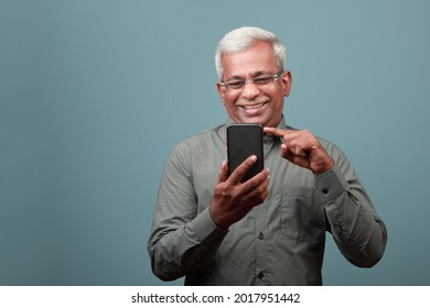 A happy man of Indian ethnicity with a smiling face engaging his mobile phone