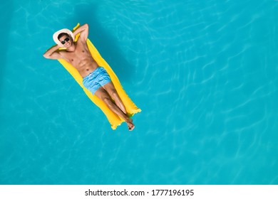 Happy man with inflatable mattress in swimming pool, top view and space for text. Summer vacation