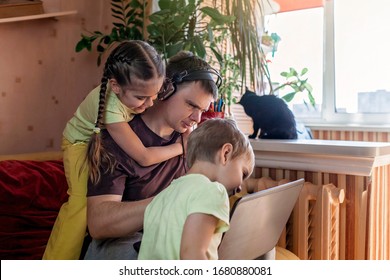 Happy man with joyful children using laptop and earphone during his home working while sitting on sofa at home, home office with together with children, life during quarantine - Powered by Shutterstock