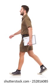 Happy man in khaki uniform walking and carrying clipboard. Full length studio shot isolated on white.