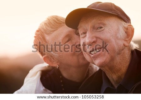 Happy man kissed by wife outside during sunset