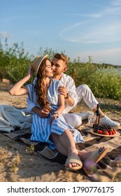 Happy Man Kissing Woman In Straw Hat Sitting Near Tasty Food And Bottle With Wine