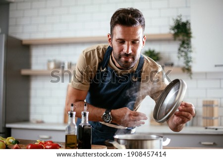 Happy man in kitchen. Young man preparing delicious food.	