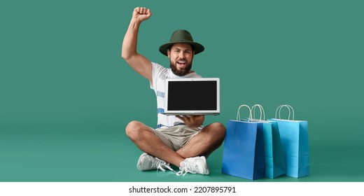 Happy man with laptop and shopping bags on green background. Black Friday sale - Powered by Shutterstock