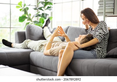 A happy man lay head on girlfriend lap looking at each other eyes. Romantic husband and wife talking relaxing in a living room at home. Young affectionate married couple spend leisure time together.  - Shutterstock ID 2067892892