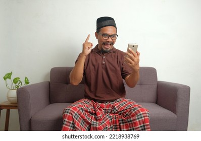 Happy Man Looking Phone Screen While Sitting In Sofa