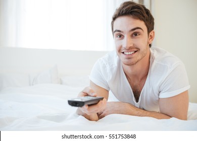 Happy Man Lying On Bed And Watching TV