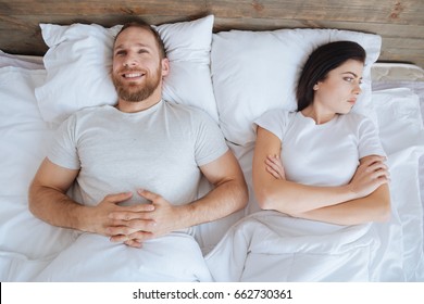 Happy Man And Mad Woman Lying In Bed Together