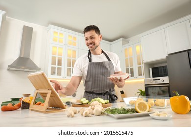 Happy Man Making Dinner While Watching Online Cooking Course Via Tablet In Kitchen