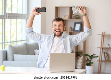 Happy man with money and mobile phone after winning his sports bet at home - Shutterstock ID 2081419996