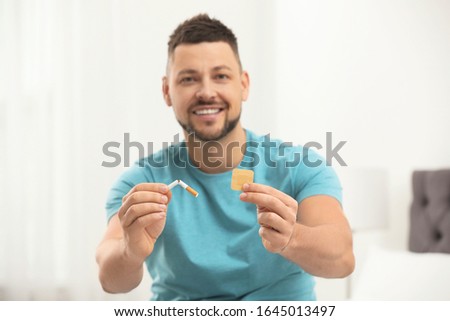 Happy man with nicotine patch and cigarette in bedroom, focus on hands