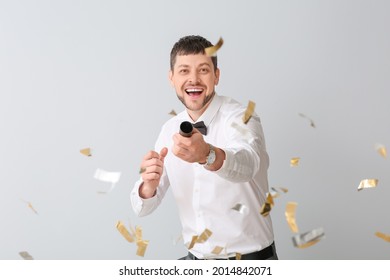 Happy Man With Noise Maker And Confetti On Light Background